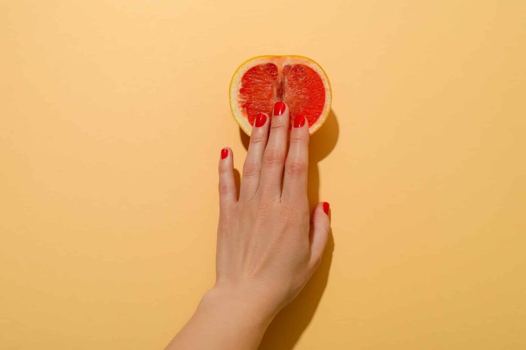 main de femme touche un fruit en forme de vagin. Concept masturbation du clitoris